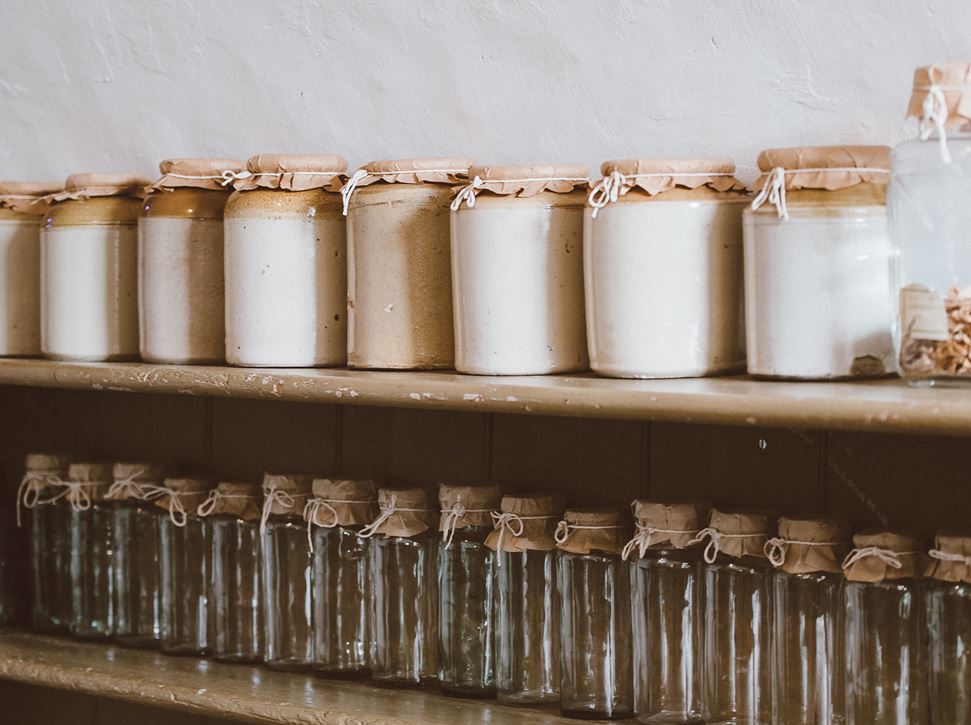 3 wooden shelves on a wall with jars all along them